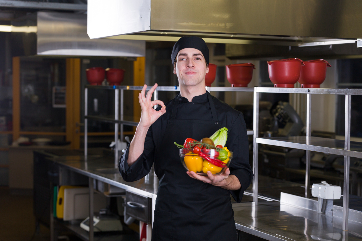 Chef de cozinha segurando uma tigela com legumes frescos e fazendo sinal de aprovação, simbolizando o protagonismo na alimentação e o cuidado com escolhas saudáveis.