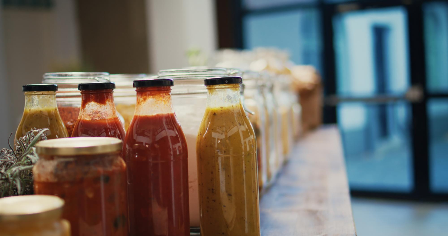 Garrafas de vidro com diferentes tipos de bebidas saudáveis alinhadas em uma prateleira, prontas para serem vendidas encaixotadas em um ambiente sustentável.